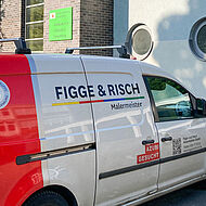 Das Firmenauto von Figge & Risch vor dem Schulgebäude einer Dortmunder Schule bei einem Schulprojekt zur Berufsorientierung für den Ausbildungsberuf Maler und Lackierer